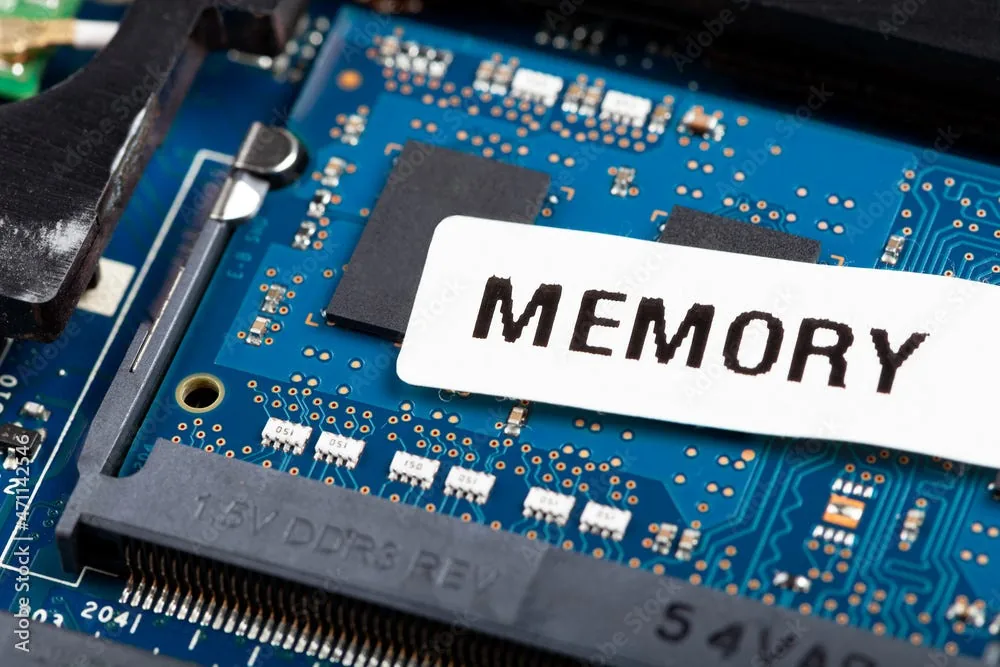 A DDR3 memory slot on a blue circuit board, with a paper label reading MEMORY laid across it